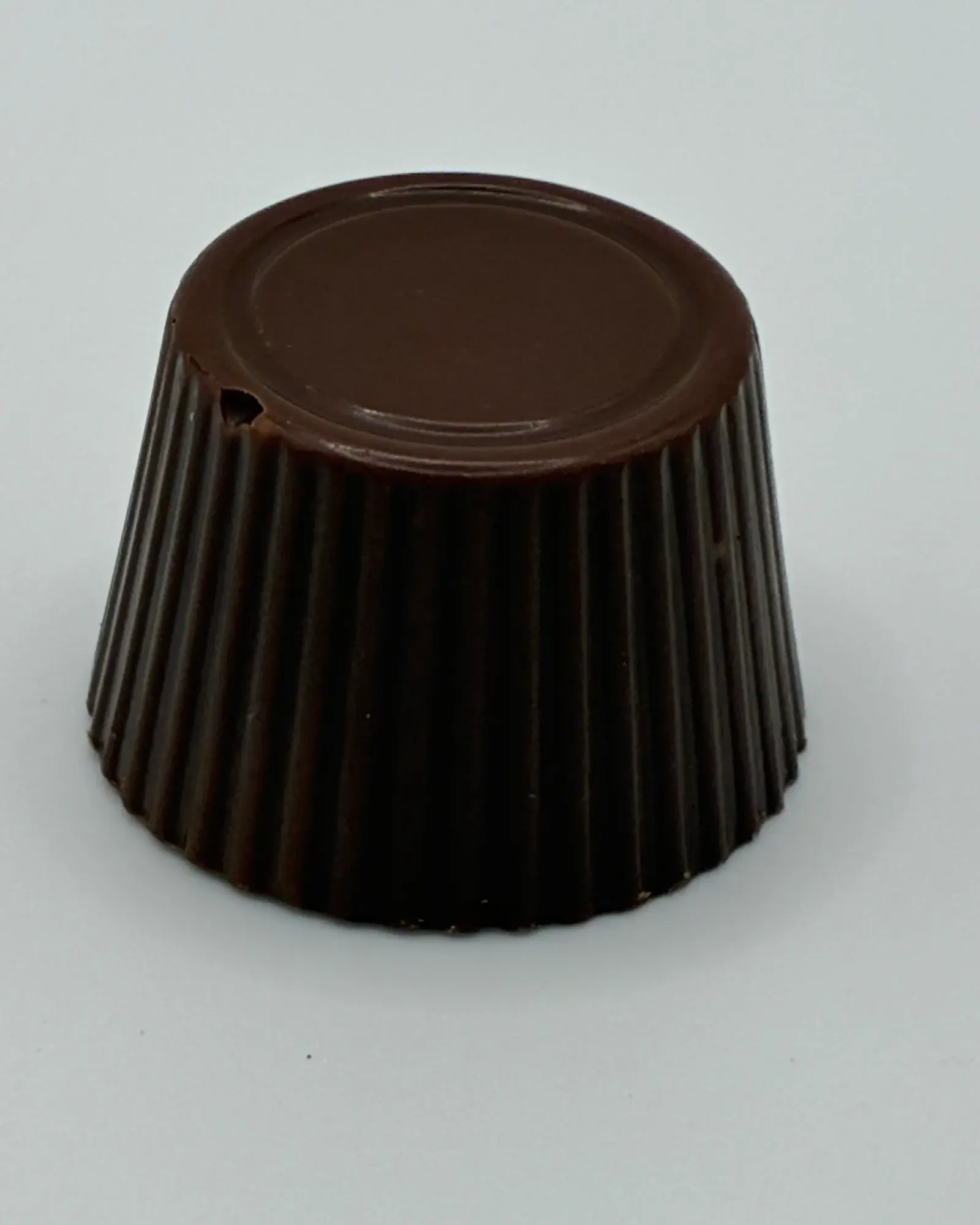 A single dark chocolate, fluted from the mould